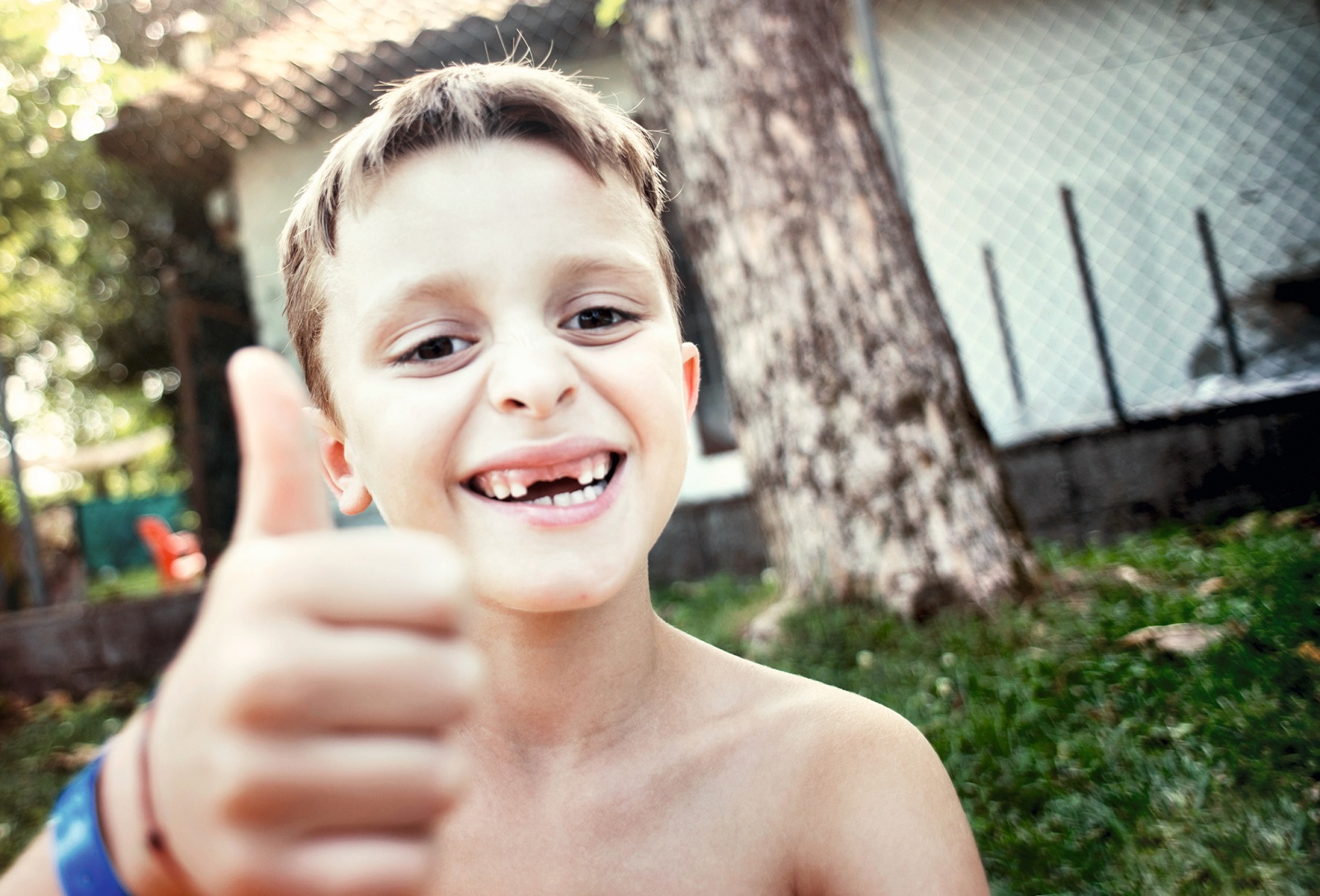 Das Bild zeigt ein Kind mit einer Zahnlücke, das einen Daumen nach oben zeigt. 