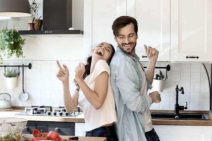 Ein Paar tanzt in der Küche, weil es von Kombiversicherungen profitiert