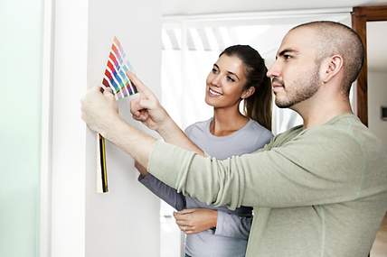 Ein junges Paar sucht sich nach dem Wohnungskauf eine neue Wandfarbe aus. 