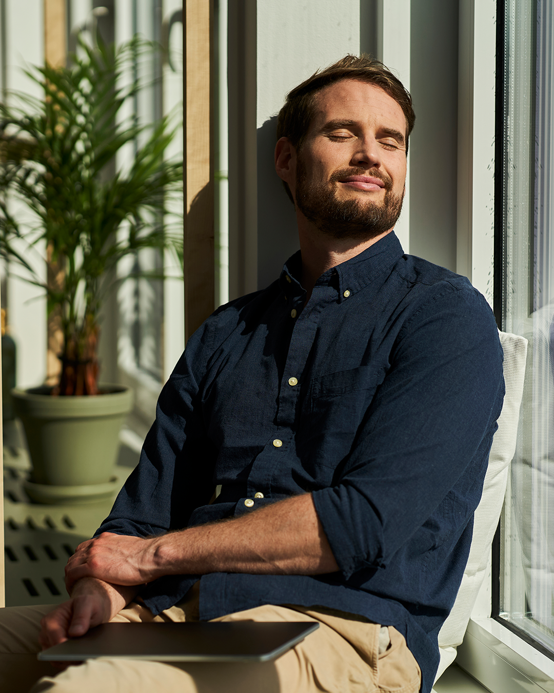 In der Sonne sitzender Mann mit geschlossenen Augen