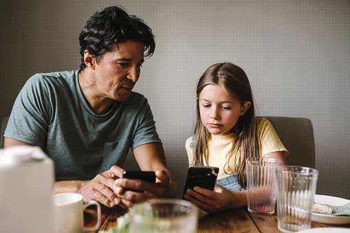 Ein Vater spricht mit seiner Tochter über die Inhalte in Socialmedia