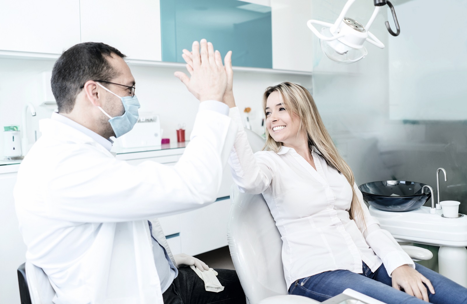 Ein Zahnarzt und seine Patientin geben sich ein High Five.