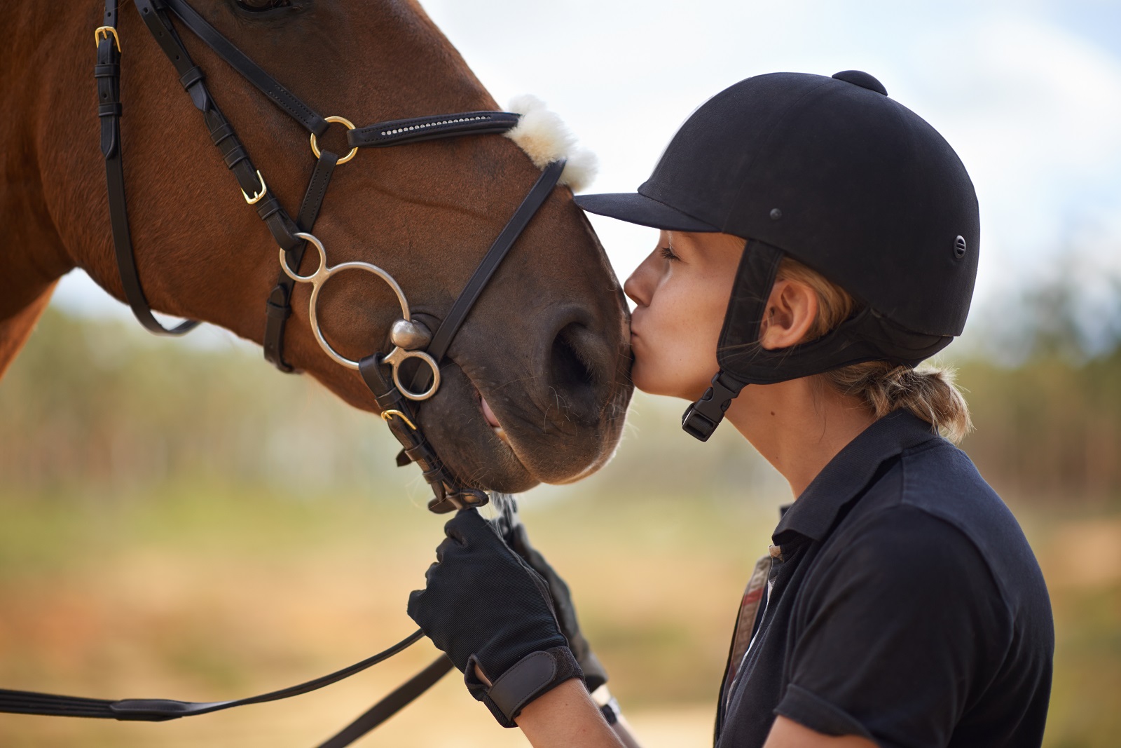 A young female rider being affectionate with her chestnut horse