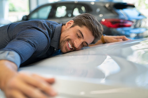 Ein Mann umarmt liebevoll ein Auto