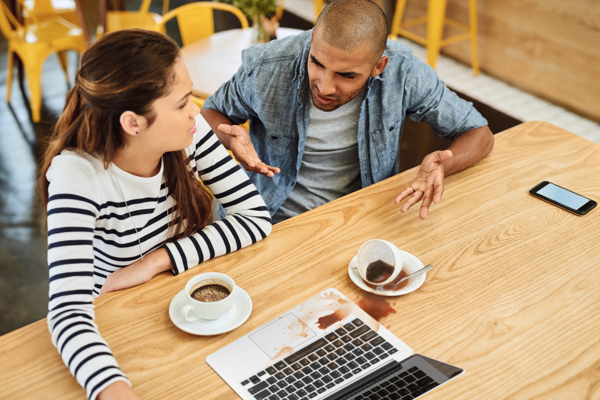 Ein Student schüttet eine Tasse Kaffee über einen Laptop.