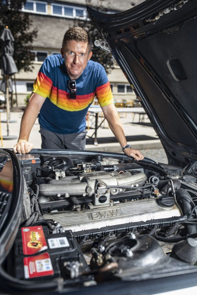Ein Mann steht vor dem offenen Motor seines Autos.