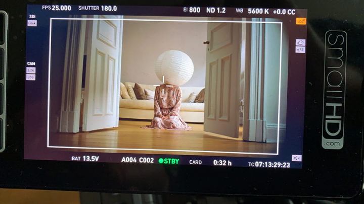 Filmszene, Mensch mit einer Papierlampe als Kopf sitzend auf dem Boden