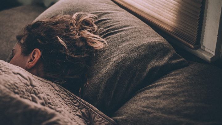 Eine schlafende Frau liegt zugedeckt im Bett