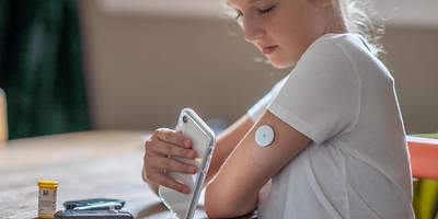 Kind mit Smartphone und Messgerät am Arm