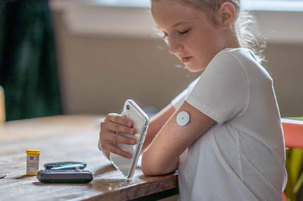 Kind mit Smartphone und Messgerät am Arm
