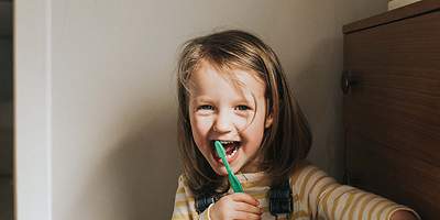 Lachendes Kind mit Zahnbürste im Mund