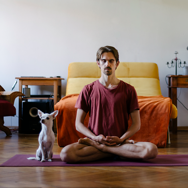Meditierender Mann mit kleinem Hund auf einer Yoga-Matte