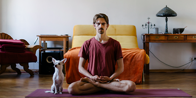 Meditierender Mann mit kleinem Hund auf einer Yoga-Matte