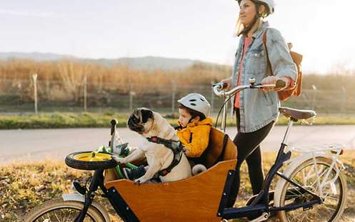 Eine Frau ist mit Ihrem Kind und Hund mit dem Rad unterwegs
