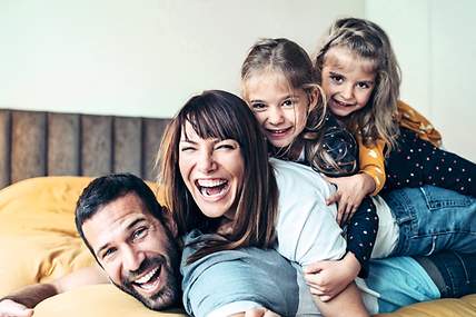 Eine Familie liegt lachend auf dem Bett.