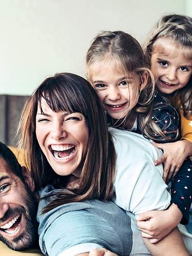 Eine Familie liegt lachend auf dem Bett.