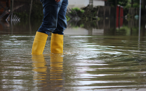 Eine Person läuft mit Gummistiefeln durch Hochwasser.