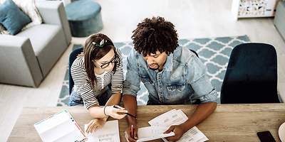 Ein junges Paar geht beim Hauskauf alle Unterlagen durch. 