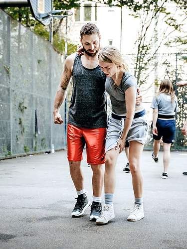 Eine Frau wird nach einem Sportunfall von einem Mann gestützt. 