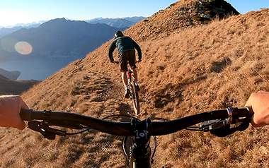 Zwei Biker heizen über einen Hügelkamm 