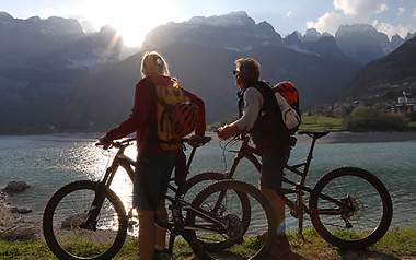 Zwei Biker machen eine Pause und blicken auf einen See