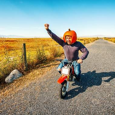 Mann mit Kürbis auf Motorrad.