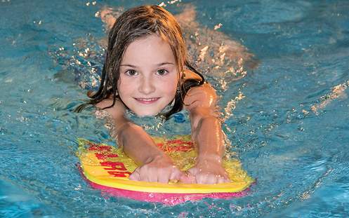 Ein Mädchen schwimmt mit einem Schwimmbrett