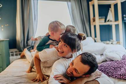 Eine Familie kuschelt lachend gemeinsam im Bett.