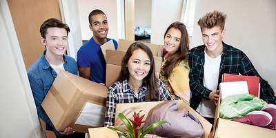 Junge lachende Menschen mit Umzugskarton in der Hand