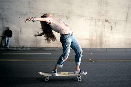 Das Bild zeigt eine junge Frau auf dem Skateboard