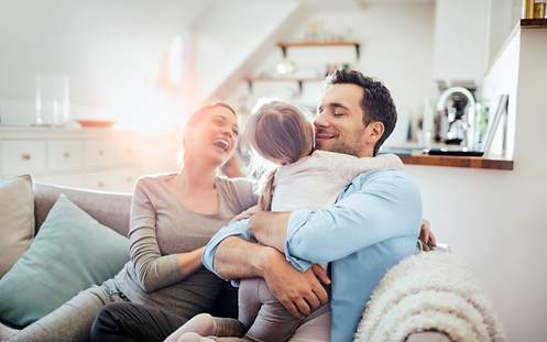 Eine Familie sitzt glücklich auf dem Sofa.