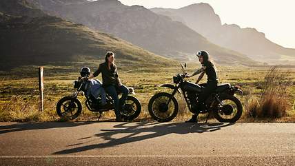 Motorradversicherung Kosten - Ein Preisbeispiel von CosmosDirekt Eine Frau schraubt an einem alten Chopper