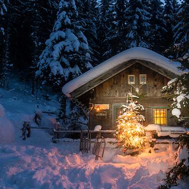 Beleuchtete Blockhütte in winterlicher Landschaft