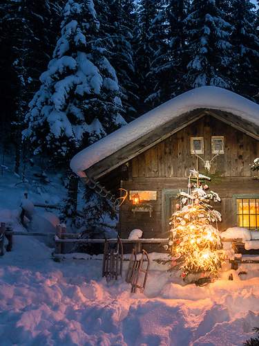 Beleuchtete Blockhütte in winterlicher Landschaft