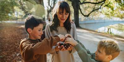 Eine Frau und zwei Kinder sammeln Kastanien