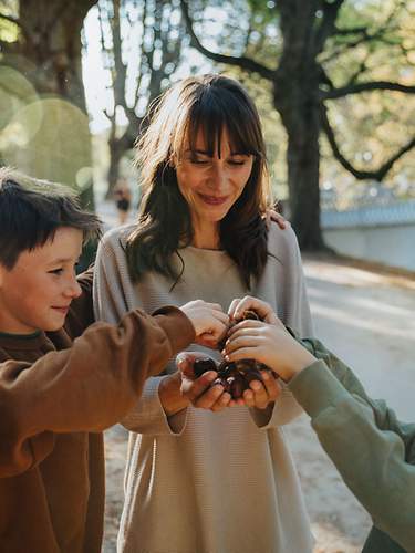 Eine Frau und zwei Kinder sammeln Kastanien