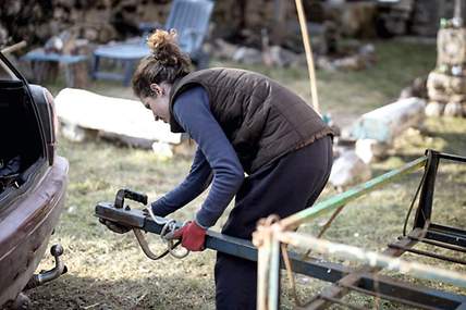 Das Bild zeigt eine Frau, die einen Anhänger an ihr Zugfahrzeug schließt.