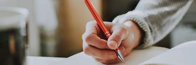 Eine Hand, die einen Stift hält und im Buch schreibt
