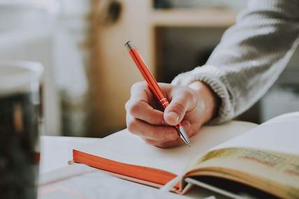 Eine Hand, die einen Stift hält und im Buch schreibt