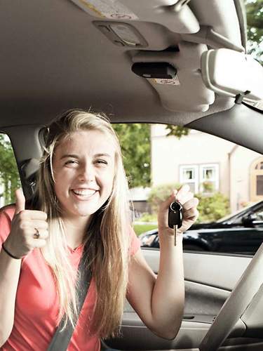 Eine Person zeigt ihren Führenschein aus dem Autofenster heraus.