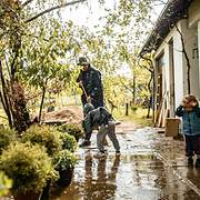 Ein Vater mit Kindern bei Starkregen im Garten.