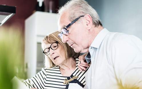 Ein Ehepaar liest gemeinsam seine Unterlagen für die Risikolebensversicherung für Rentner.