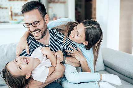 Eine Familie spielt sorglos auf dem Sofa, da Kinder durch die Risikolebensversicherung abgesichert sind.