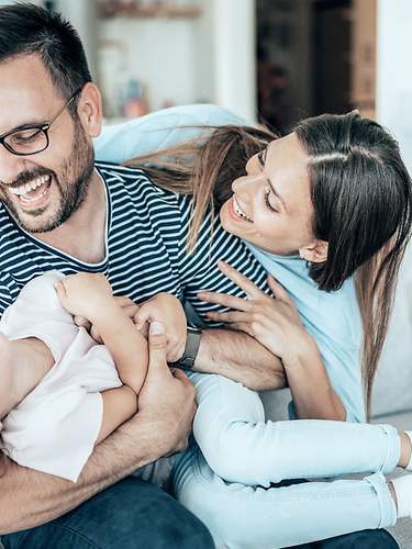 Eine Familie spielt sorglos auf dem Sofa, da Kinder durch die Risikolebensversicherung abgesichert sind.