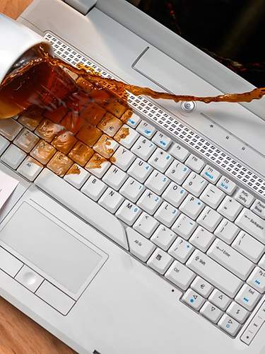 Das Bild zeigt, wie eine Tasse Kaffee über einem Laptop verschüttet wird.