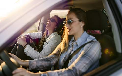 Zwei junge Frauen sitzen glücklich in einem Toyota.