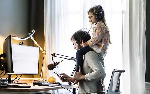 Welche beruflichen Versicherungen sind von der Steuer absetzbar? Ein Vater arbeitet im Homeoffice, während seine Tochter auf seinen Schultern sitzt.