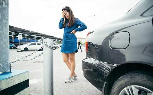 Eine junge Frau ärgert sich über die Kratzer in ihrem Auto. 
