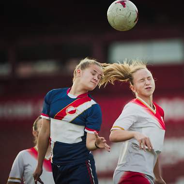 Zwei Fußballspielerinnen springen für einen Kopfball in die Luft 