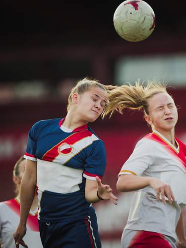 Zwei Fußballspielerinnen springen für einen Kopfball in die Luft 
